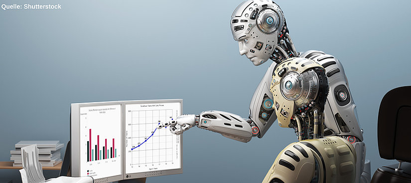 Das Bild zeigt einen hochdetaillierten und stilisierten Roboter, der an einem Schreibtisch sitzt. Der Roboter scheint Diagramme auf zwei Blättern Papier zu untersuchen, was darauf hindeuten könnte, dass er Daten analysiert oder an einem Projekt arbeitet, das Statistiken oder Prognosen beinhaltet. Das Design des Roboters ist futuristisch mit sichtbaren komplizierten mechanischen Teilen, was auf fortgeschrittene Technologie schließen lässt. Der Hintergrund ist schlicht gehalten und lenkt die Aufmerksamkeit des Betrachters auf den Roboter und seine Aufgabe. Der Text "Quelle: Shutterstock" weist darauf hin, dass die Bildquelle Shutterstock ist